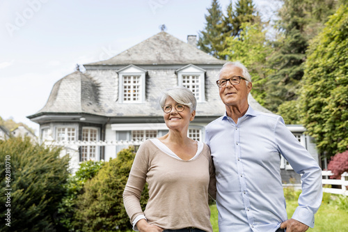 Smiling senior couple standing in garden of their home photo