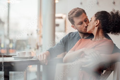 Young woman kissing man while sitting together at cafe