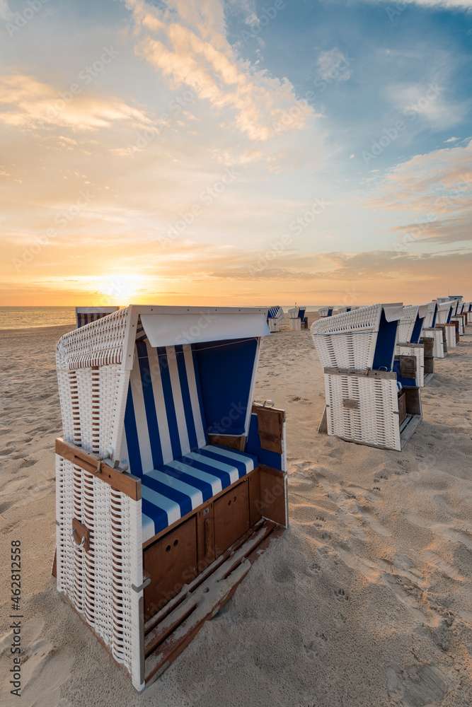 Germany, Sylt, North Sea, sandy beach with hooded beach chairs in sunset Germany, Sylt, North Sea, sandy beach with hooded beach chairs in sunset