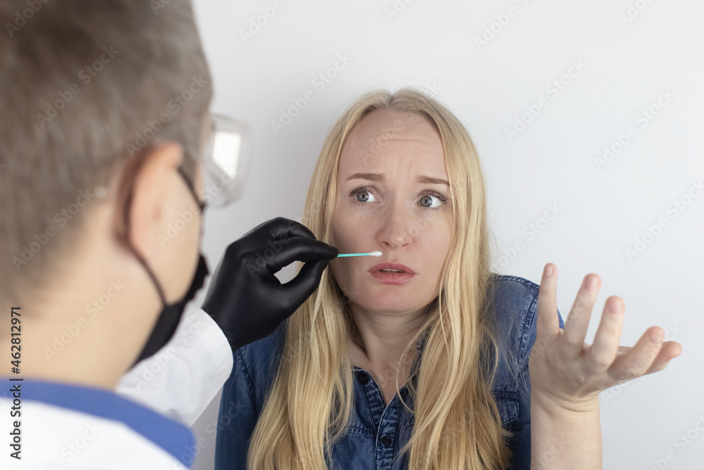 Fototapeta premium The girl complains to the doctor about the loss of smell. The doctor conducts a sense of smell test. Diagnostics of covid-19. Symptoms of the coronavirus. Quarantine and isolation. Test for sars-cov-2