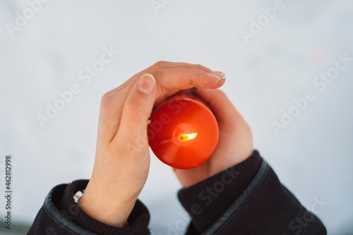 Close-up of young woman hands holding candle over snow covered land photo