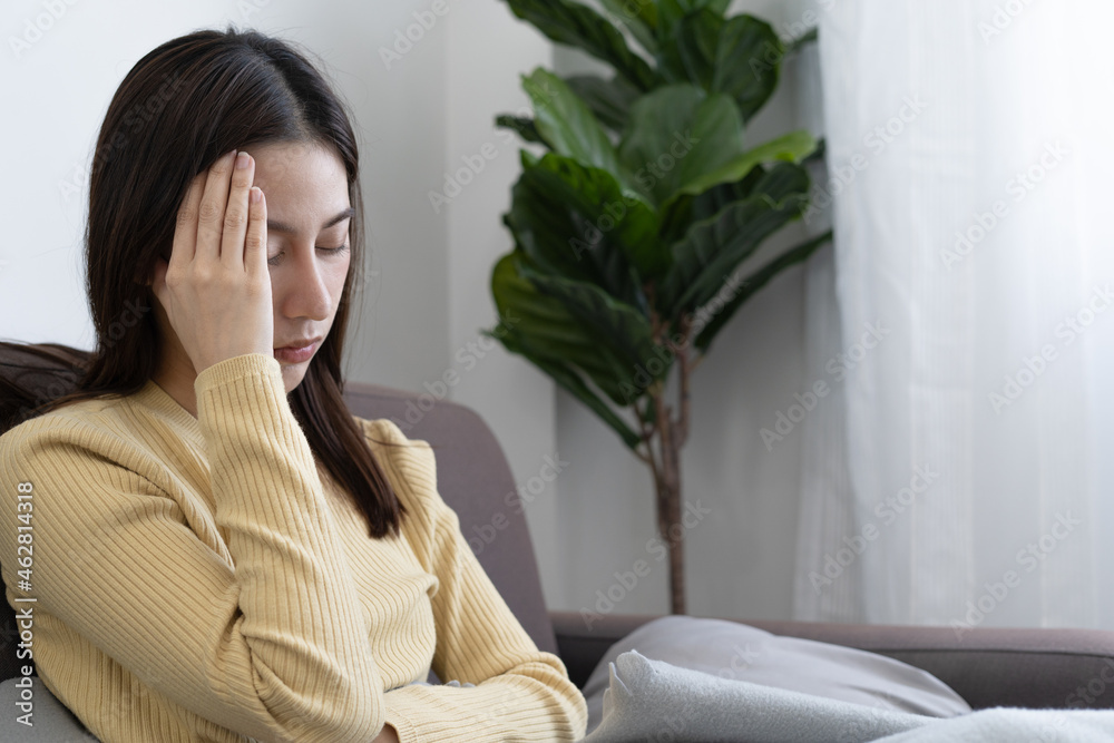 Upset woman feels a migraine headache or depression or sick. Disappointed Asian woman touches her forehead and has a high fever. Upset woman feels a migraine headache or depression or sick. Disappointed Asian woman touches her forehead and has a high fever.