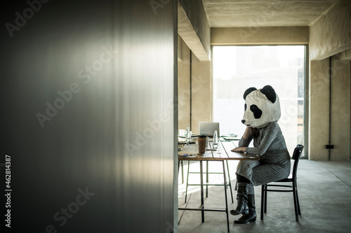 Woman with panda mask sitting in office, thinking photo