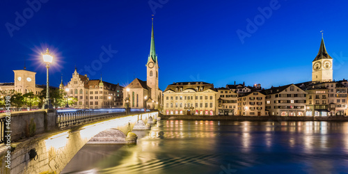 Switzerland, Canton of Zurich, Zurich, River Limmat and old town buildings along illuminated Limmatquai street at dusk photo