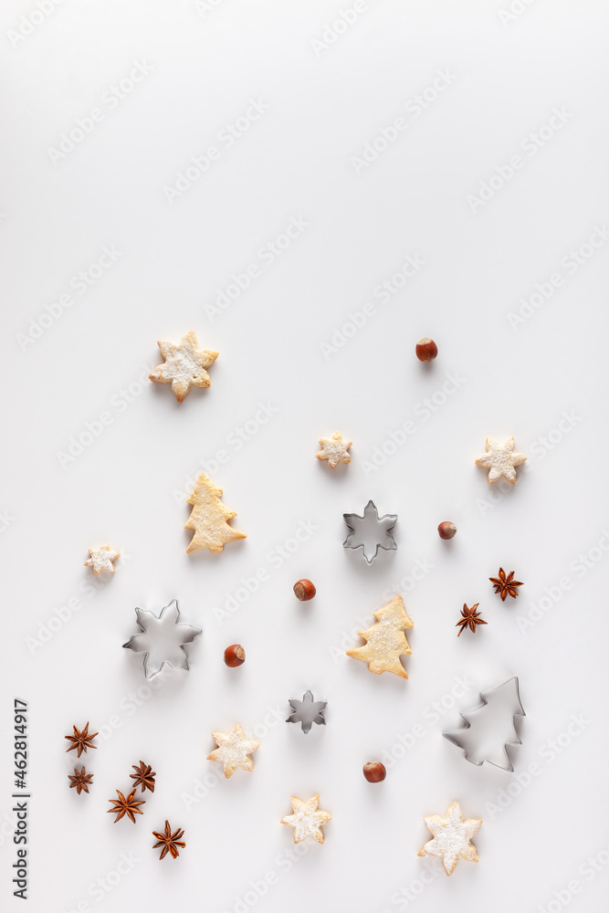 Christmas composition is made of Christmas cookies, cookie cutters, nuts and anice stars on white background. Copy space.
