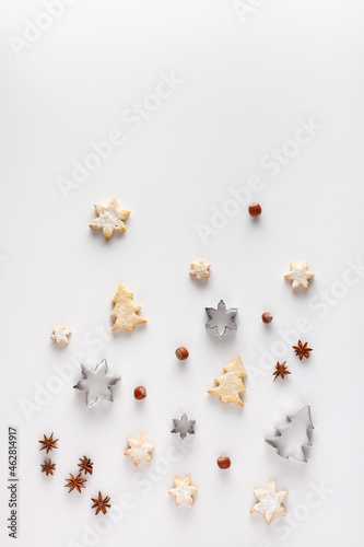 Christmas composition is made of Christmas cookies, cookie cutters, nuts and anice stars on white background. Copy space. 