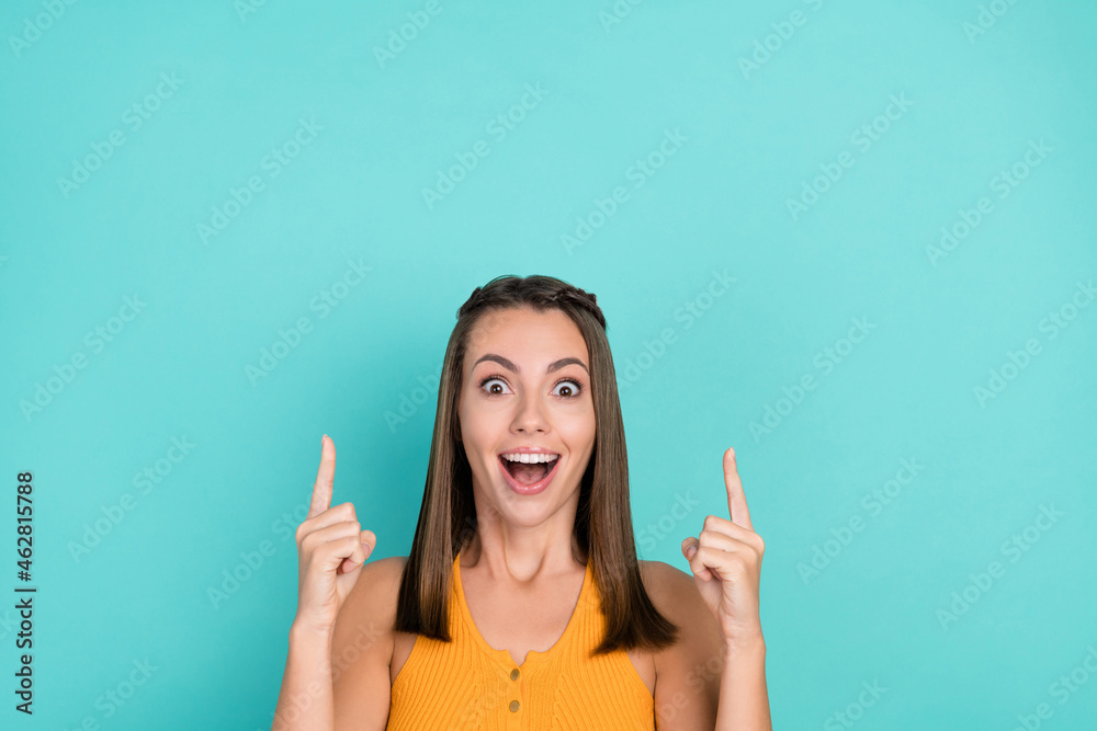 Photo of surprised cheerful happy young woman point finger up empty space news isolated on teal color background Photo of surprised cheerful happy young woman point finger up empty space news isolated on teal color background
