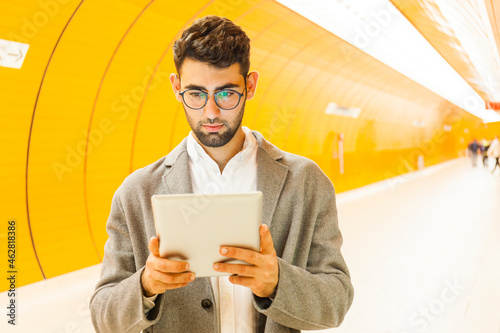 Germany, Munich, portrait of young businessman using digital tablet at underground station photo