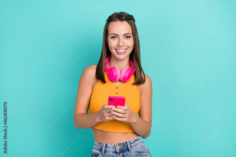 Photo of joyful cheerful positive woman hold hands telephone music headphones isolated on teal color background Photo of joyful cheerful positive woman hold hands telephone music headphones isolated on teal color background