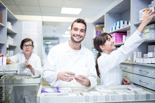 Smiling pharmacists working at cabinet in pharmacy photo