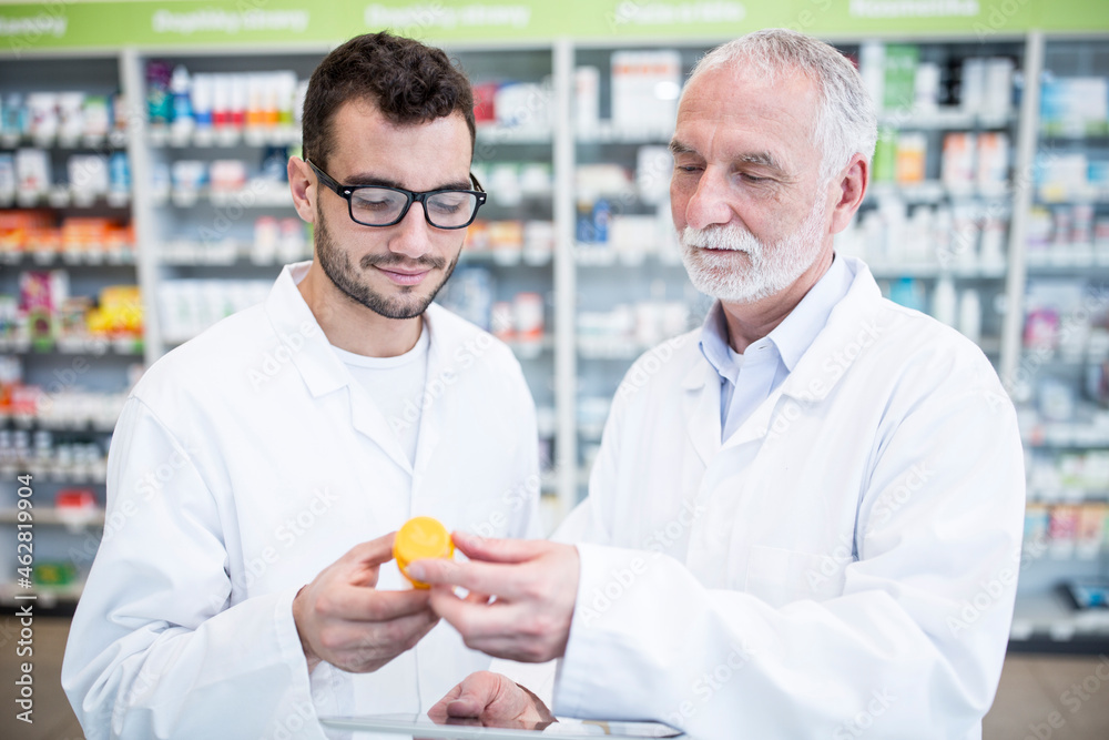 Two pharmacists examining medicine in pharmacy Two pharmacists examining medicine in pharmacy