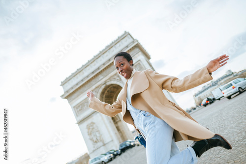 Cheerful young woman against Arc de Triomphe during sunny day, Paris, France photo
