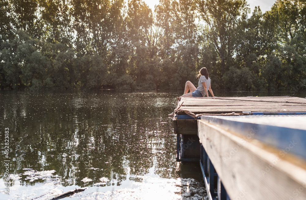 Relaxed woman sitting on jetty at a remote lake Relaxed woman sitting on jetty at a remote lake