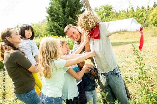 School children on an outing poting scarecrow in a field photo