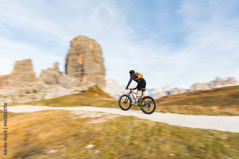 Italy, Cortina d'Ampezzo, panning view of man cycling with mountain bike in the Dolomites mountains Italy, Cortina d'Ampezzo, panning view of man cycling with mountain bike in the Dolomites mountains