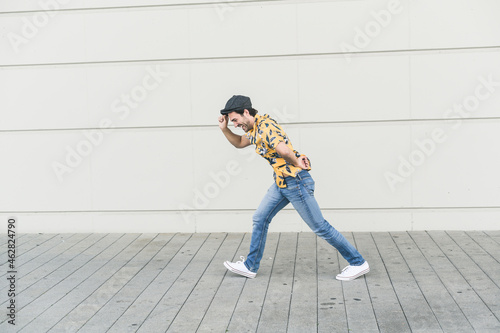 Young man wearing flat hat and aloa shirt, walking against headwind photo