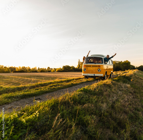happy couple waving and cheering out of their camper, having fun on their road trip