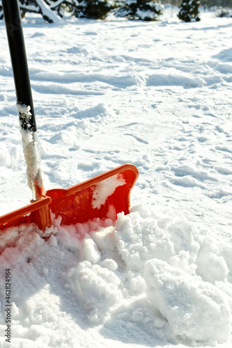 Plastic snow shovel left in snowdrift. Winter chores. Copy space.