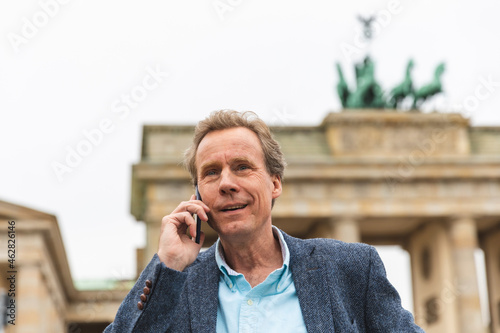 Portrait of smiling senior man on the phone at  Brandenburg Gate, Berlin, Germany photo