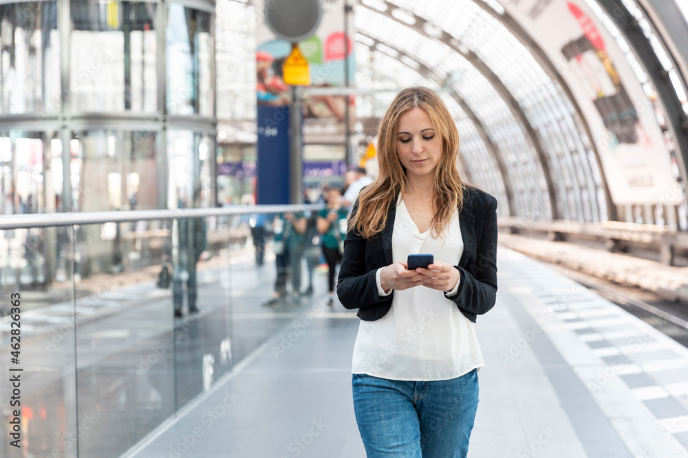 Woman using smartphone on the station platform, Berlin, Germany Woman using smartphone on the station platform, Berlin, Germany