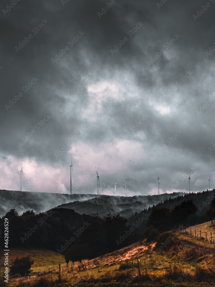 dramatische Landschaftsaufnahme eines Windparks mit bedecktem Himmel und Nebel