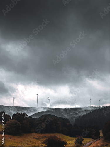 dramatische Landschaftsaufnahme eines Windparks mit bedecktem Himmel und Nebel