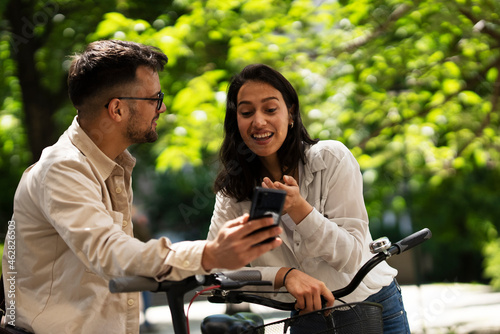 Happy funny couple with bicycle in the park. Loving couple enjoying together outdoors..