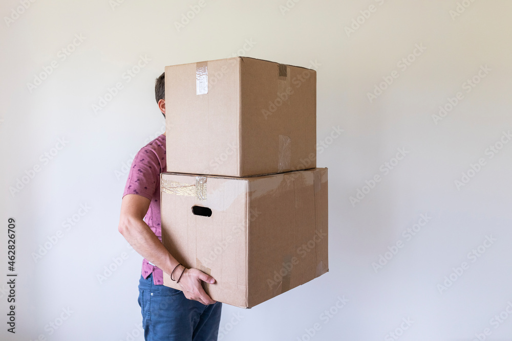 Man moving into new home carrying cardboard boxes Man moving into new home carrying cardboard boxes