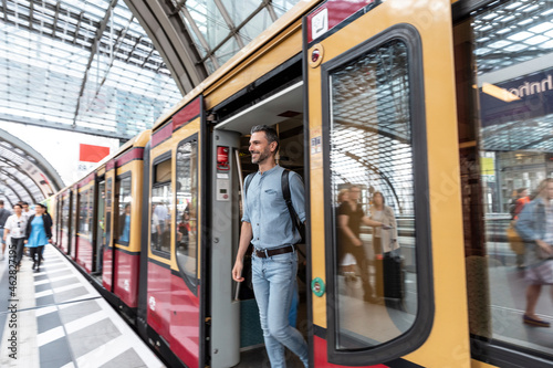 Smiling man getting out of the train at the station platform, Berlin, Germany
