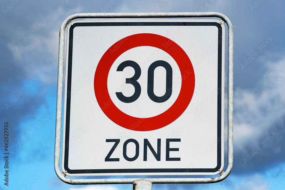 Tempolimit Zone 30 Schild vor blauen und leicht bewölktem Himmel Tempolimit Zone 30 Schild vor blauen und leicht bewölktem Himmel