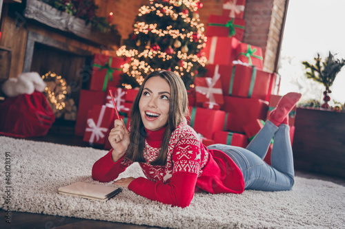 Full body photo of impressed millennial lady lie on floor think wishes wear new year sweater jeans socks at home alone on christmas eve