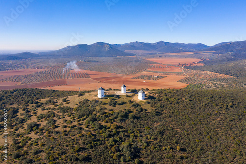 Spain, Province of Ciudad Real, Puerto Lapice, Aerial view of three windmills standing on top of hill photo
