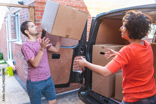 Couple unloading cardboard boxes from van photo