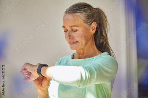 Confident woman checking the time against wall at home photo