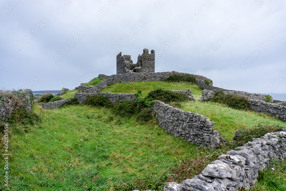 old castle ruin of a tower on a green grass hill on the Aran Islands