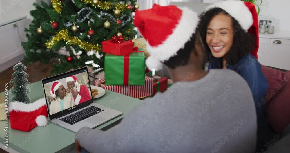 Happy african american couple on video call on laptop with senior couple at christmas time Happy african american couple on video call on laptop with senior couple at christmas time