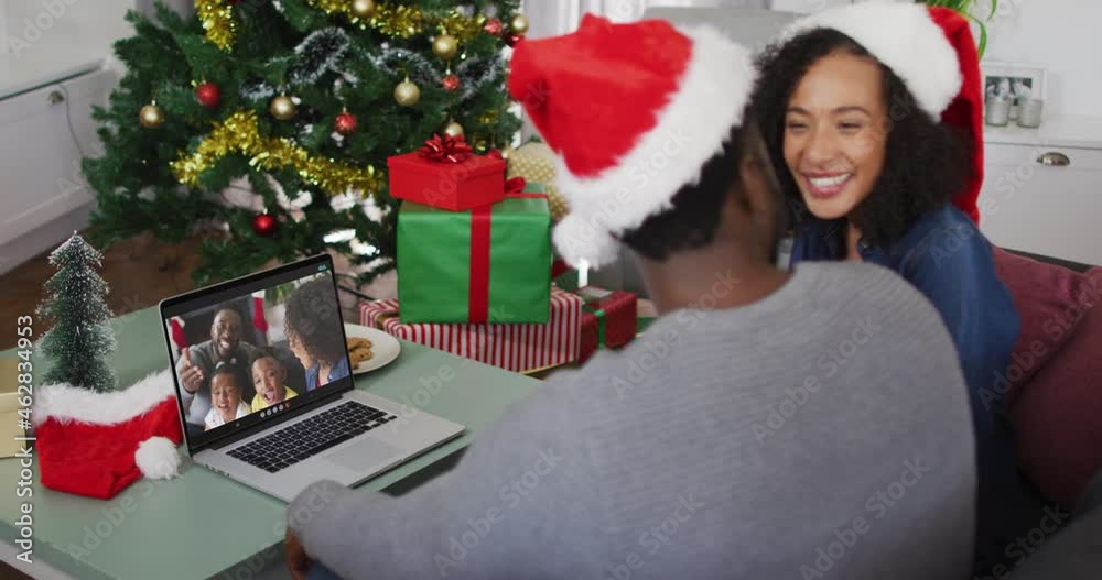 Happy african american couple on video call on laptop with family at christmas time Happy african american couple on video call on laptop with family at christmas time