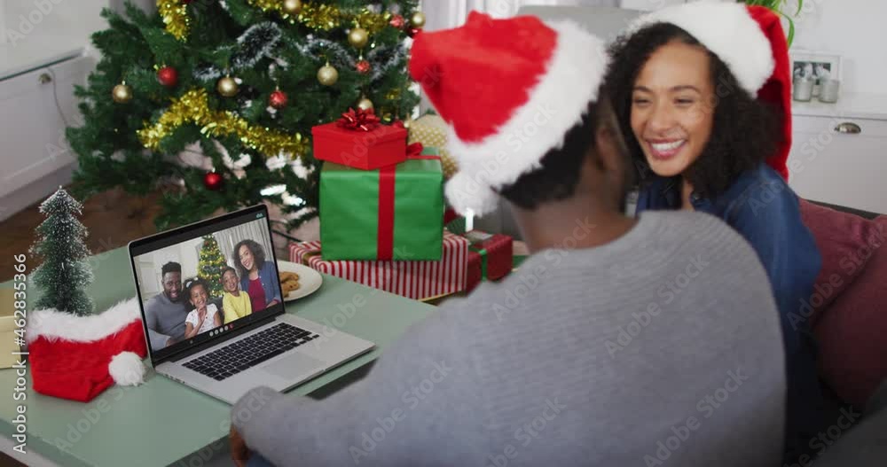 Happy african american couple on video call on laptop with family at christmas time Happy african american couple on video call on laptop with family at christmas time