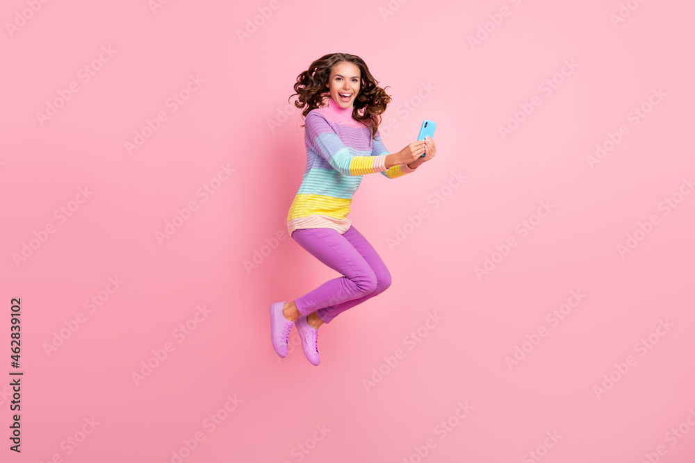 Full body profile side photo of young girl blogger use smartphone jump fly isolated over pastel color background Full body profile side photo of young girl blogger use smartphone jump fly isolated over pastel color background