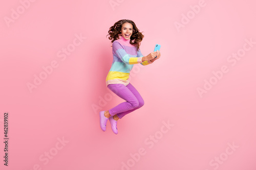 Full body profile side photo of young girl blogger use smartphone jump fly isolated over pastel color background