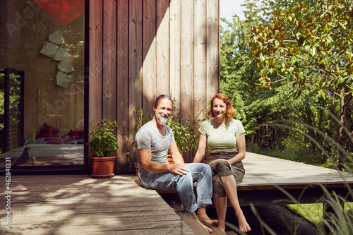 Smiling couple relaxing while sitting outside tiny house photo