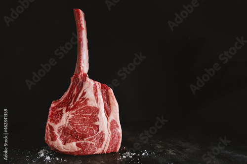 Fresh tomahawk steak on old board photo