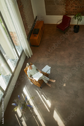 Senior man sitting on chair in a loft flat reading newspaper photo