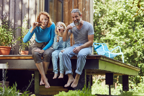 Parents with daughter brushing teeth while sitting outside tiny house photo