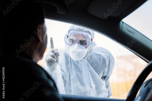Man wearing protective clothing reprimanding senior man in car photo