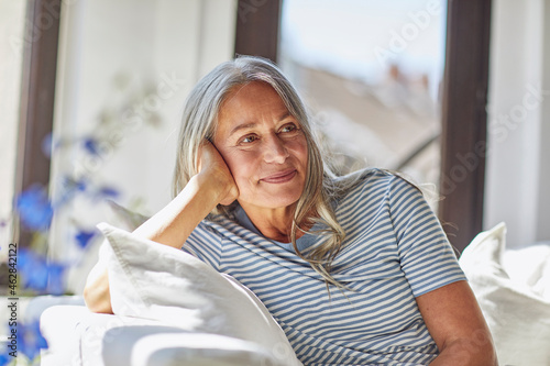 Smiling woman relaxing on sofa in living room photo