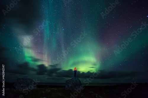 Norway, Lofoten Islands, Eggum, man standing on rock and watching northern lights photo