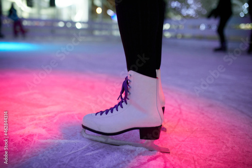 Leg of woman wearing ice skates standing on an ice rink photo