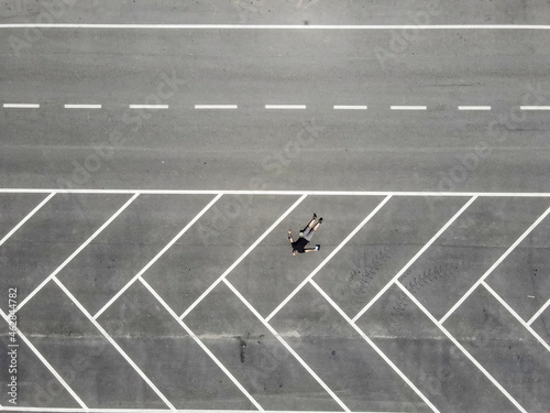 Drone view of man lying on back in empty parking lot photo
