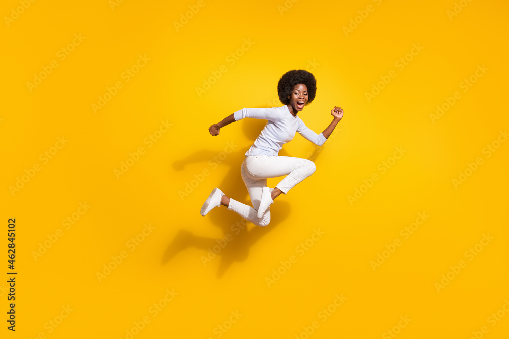 Full body profile side photo of afro american young woman jump up run wear white pullover pants isolated on yellow color background